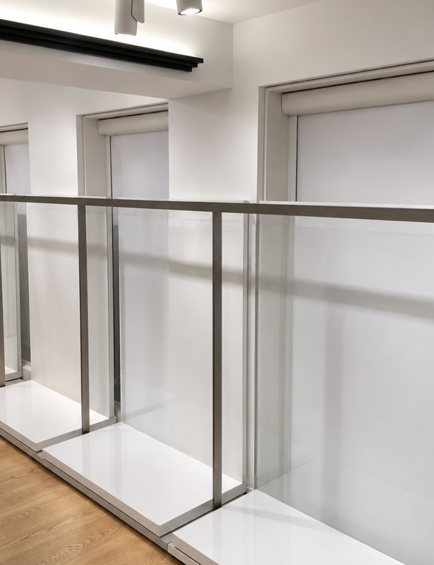 Decorquip white cassetted roller blinds with Capital Collection fabric lowered in a modern commercial interior behind a glass balustrade