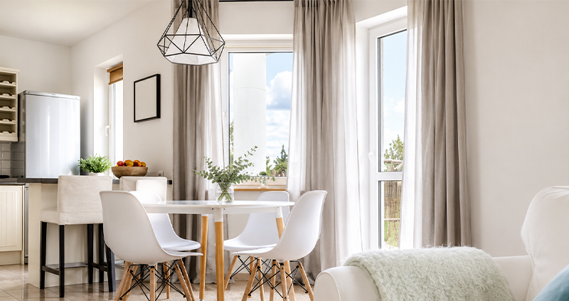 Decorquip light beige curtains framing large patio doors in a modern open-plan dining and living room