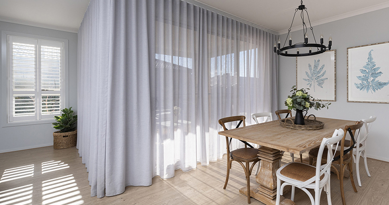 Decorquip white sheer curtains surrounding corner patio doors in a modern dining room
