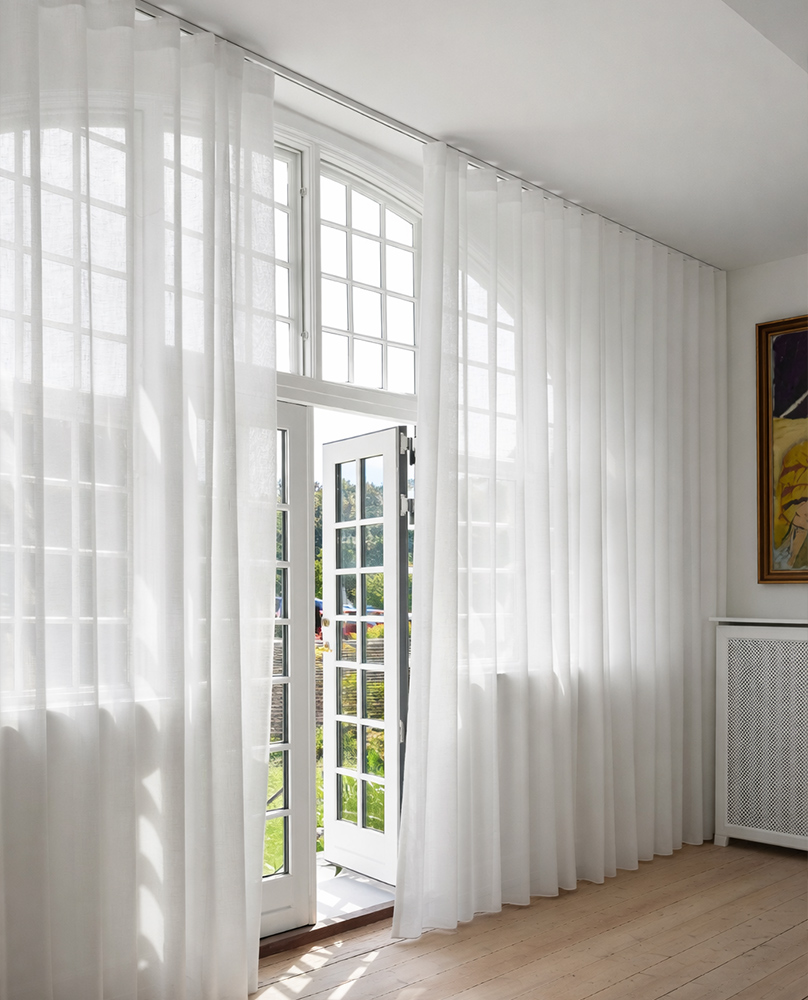 Decorquip white sheer curtains on a ceiling-mounted track framing tall arched French doors in a bright living room