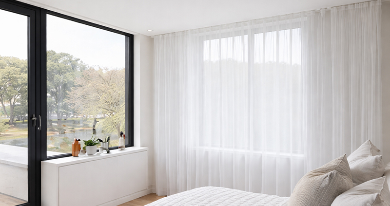 Decorquip white sheer curtains across a large bedroom window with black-framed glazing