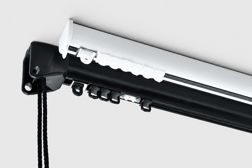 Decorquip ceiling-mounted black corded curtain track showing white master carriers, gliders and operating cord in a product studio