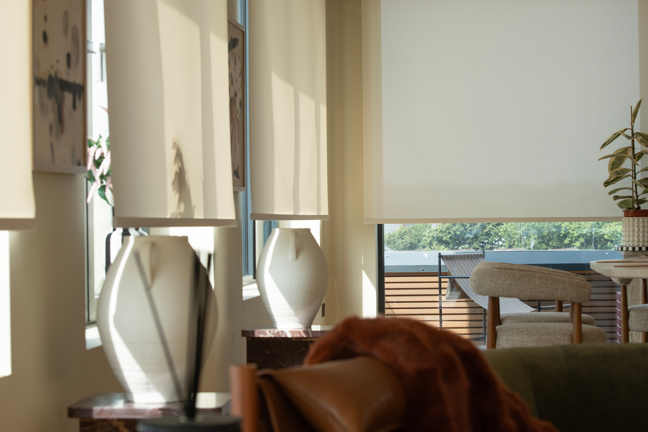Decorquip cream roller blinds partially lowered across wide living room windows