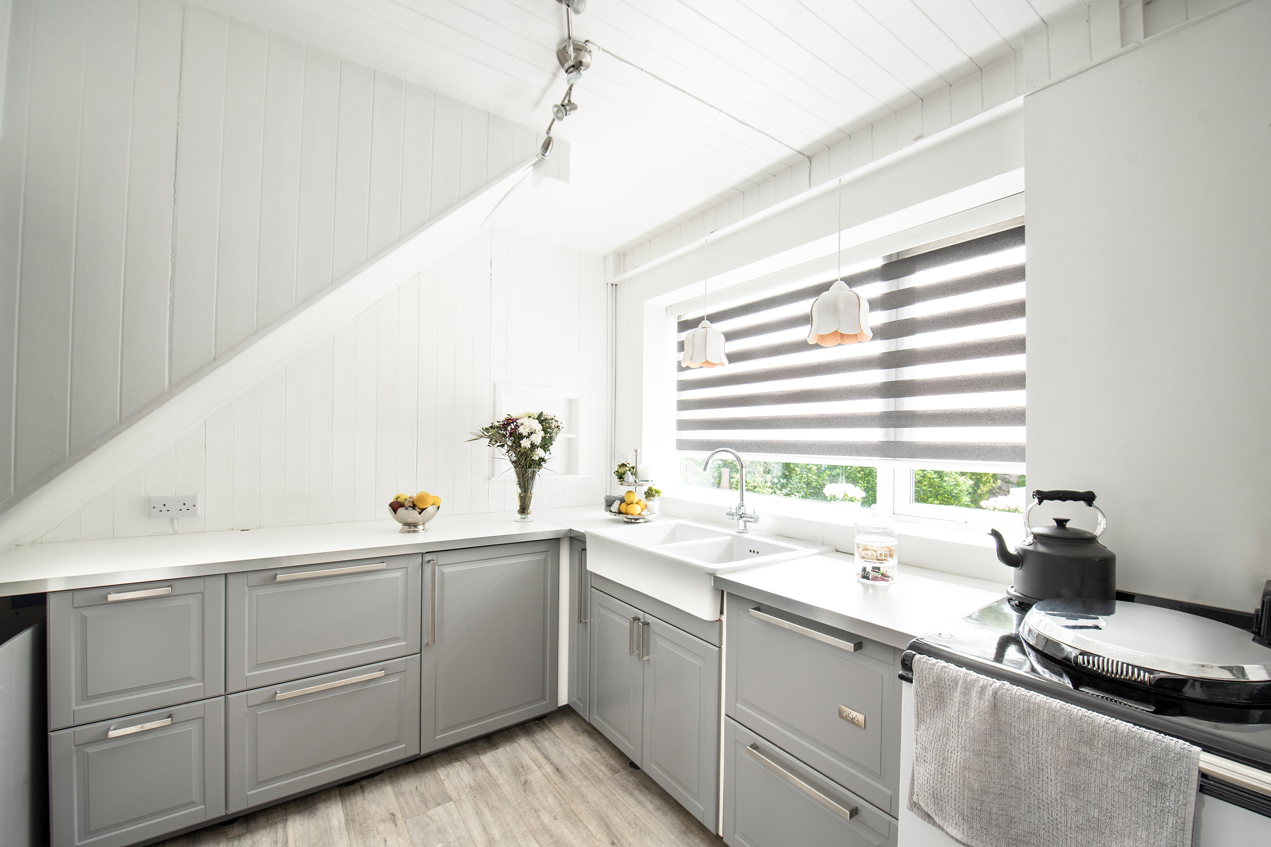 Decorquip grey day and night blind with alternating sheer panels above a white kitchen sink