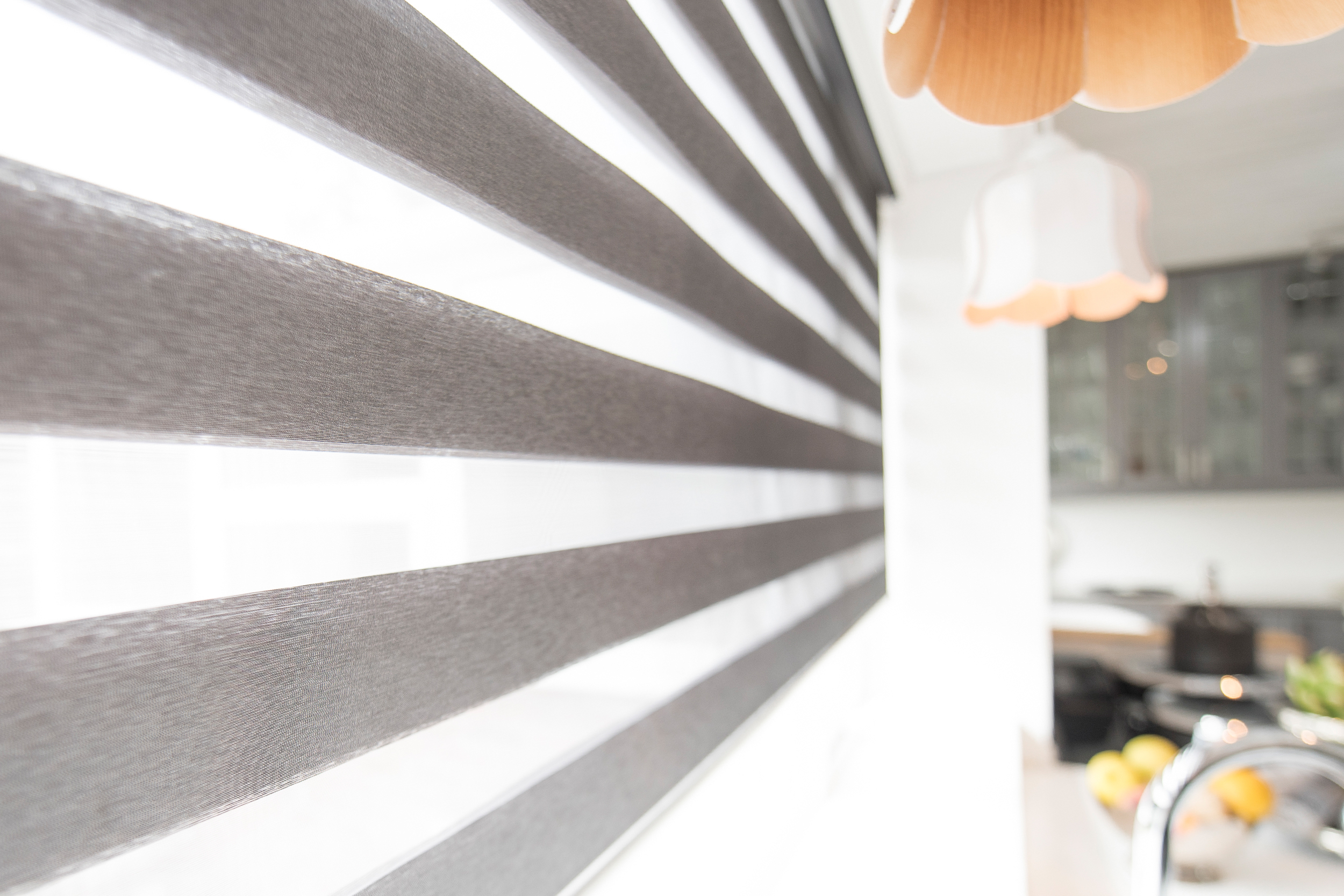 Decorquip grey day and night blind with alternating sheer panels above a white kitchen sink