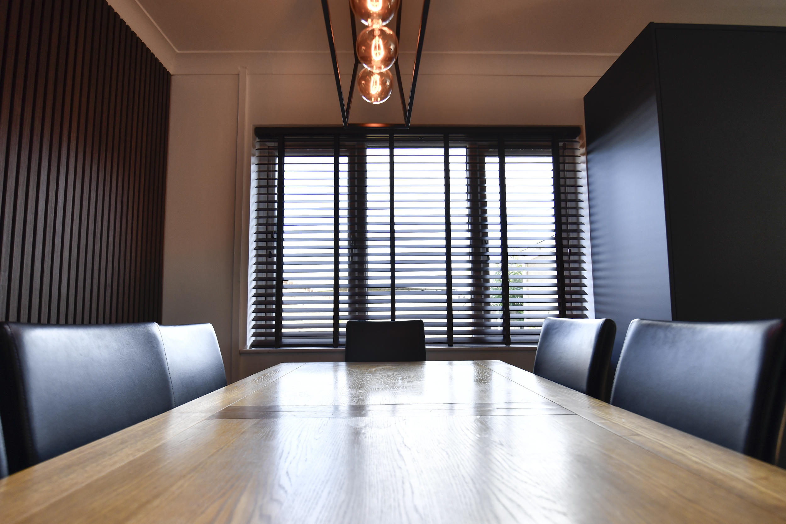 Decorquip dark faux wood Venetian blinds partially open in a modern dining room