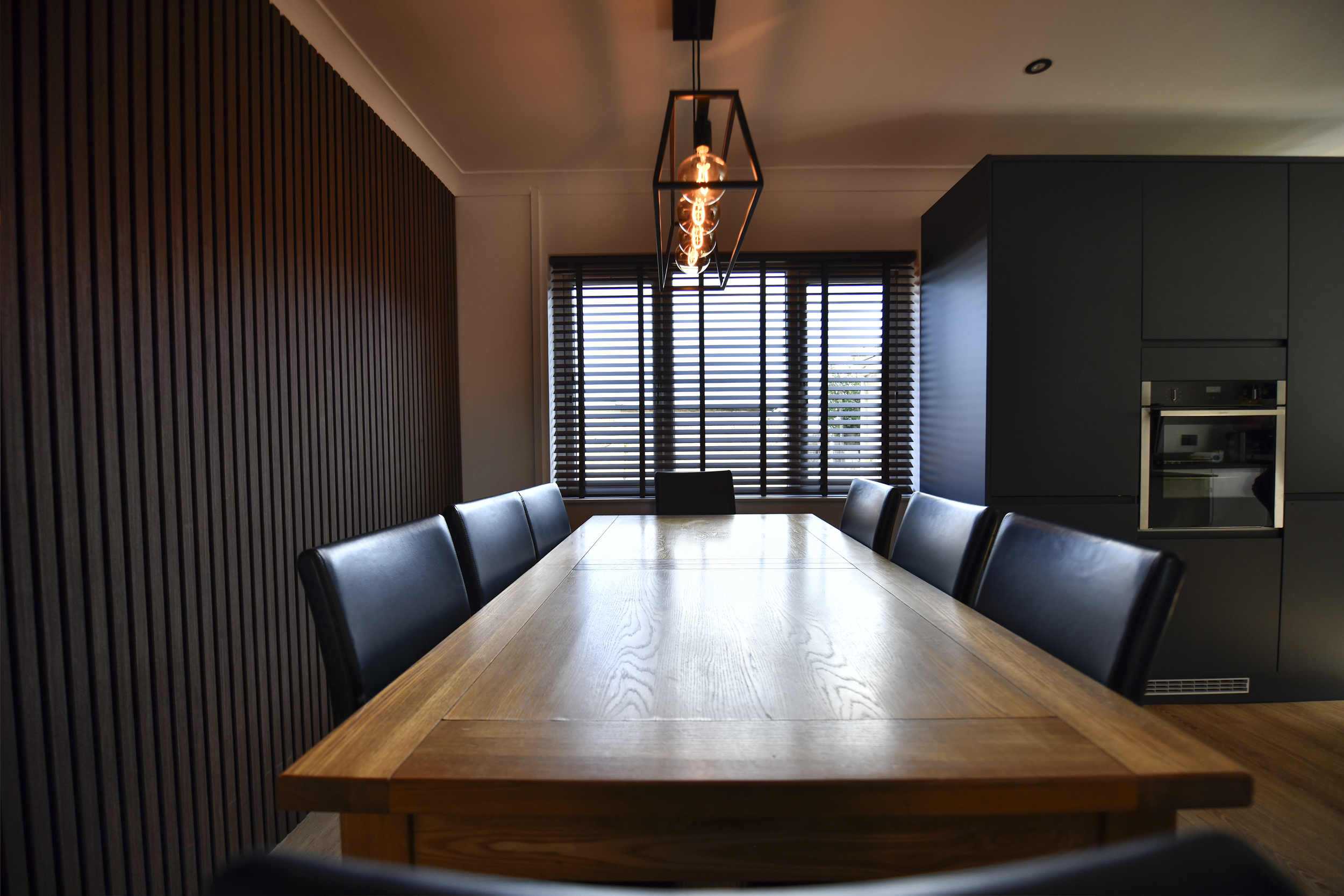 Decorquip dark faux wood Venetian blinds partially open in a modern dining room