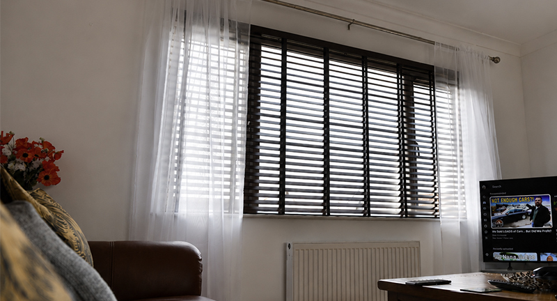 Decorquip dark faux wood Venetian blind with sheer white curtains in a living room