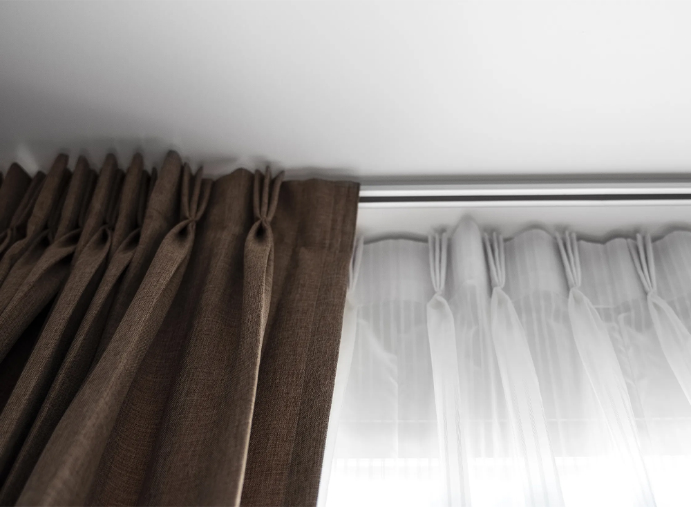Decorquip brown curtains with white sheer curtains on a ceiling-mounted motorised curtain track in an interior setting