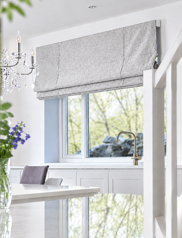 Decorquip light grey textured XL Roman blind partially lowered above a kitchen window